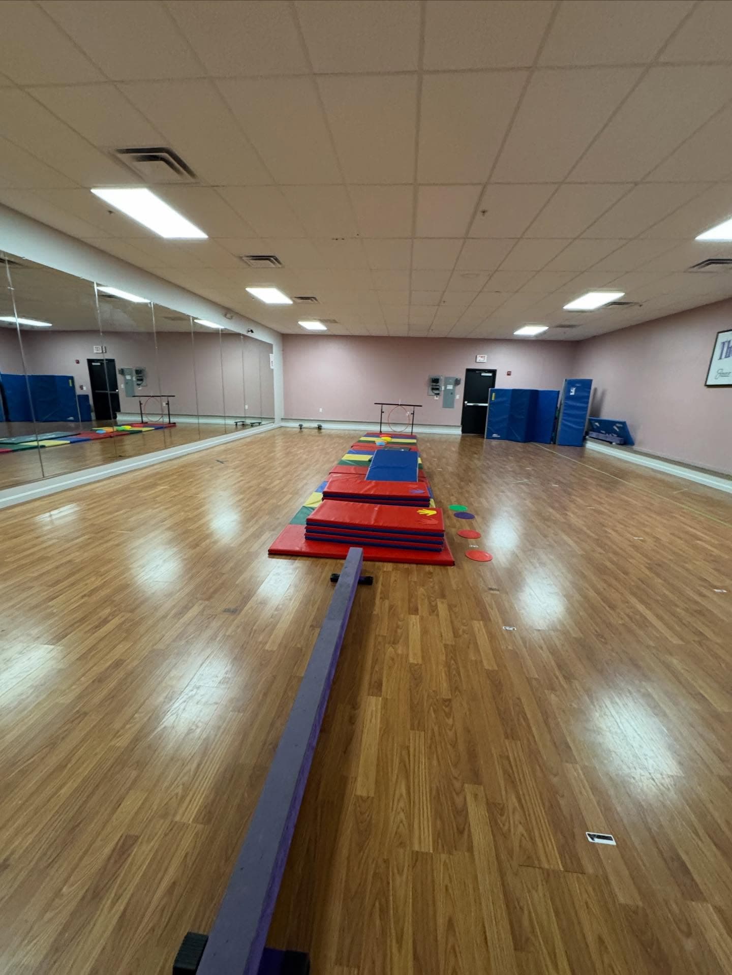 The main dance studio with mirrors, balance beam, and colorful mats